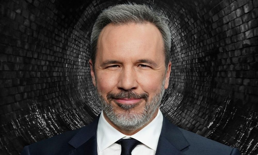 دنی ویلنوو در کنار پوستر رسمی فیلم جیمز باند جدید